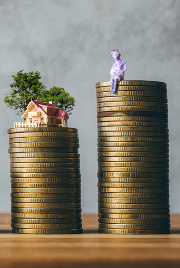 coins stacked up with man and house on top